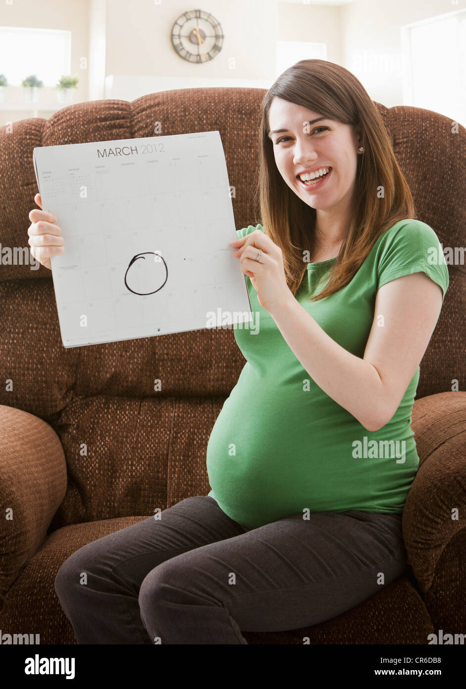 Portrait of pregnant woman showing calendar with due date Stock Photo