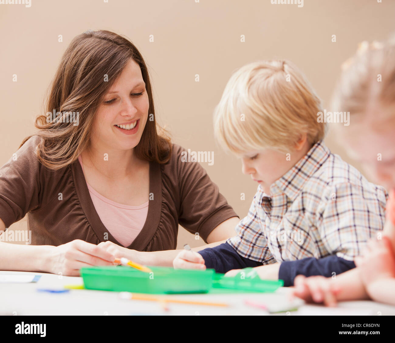 Mid adult woman teaching boy (4-5) drawing in kindergarten Stock Photo
