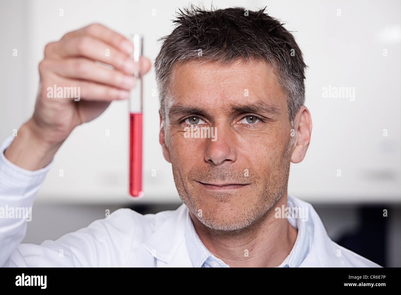 Germany, Bavaria, Munich, Scientist holding red liquid in test tube for medical research in laboratory Stock Photo
