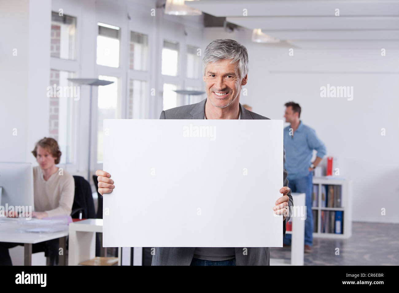 Germany, Bavaria, Munich, Mature man holding placard in office Stock Photo