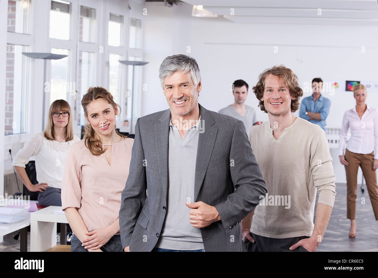 Germany, Bavaria, Munich, Mature man with colleagues standing in office, smiling Stock Photo