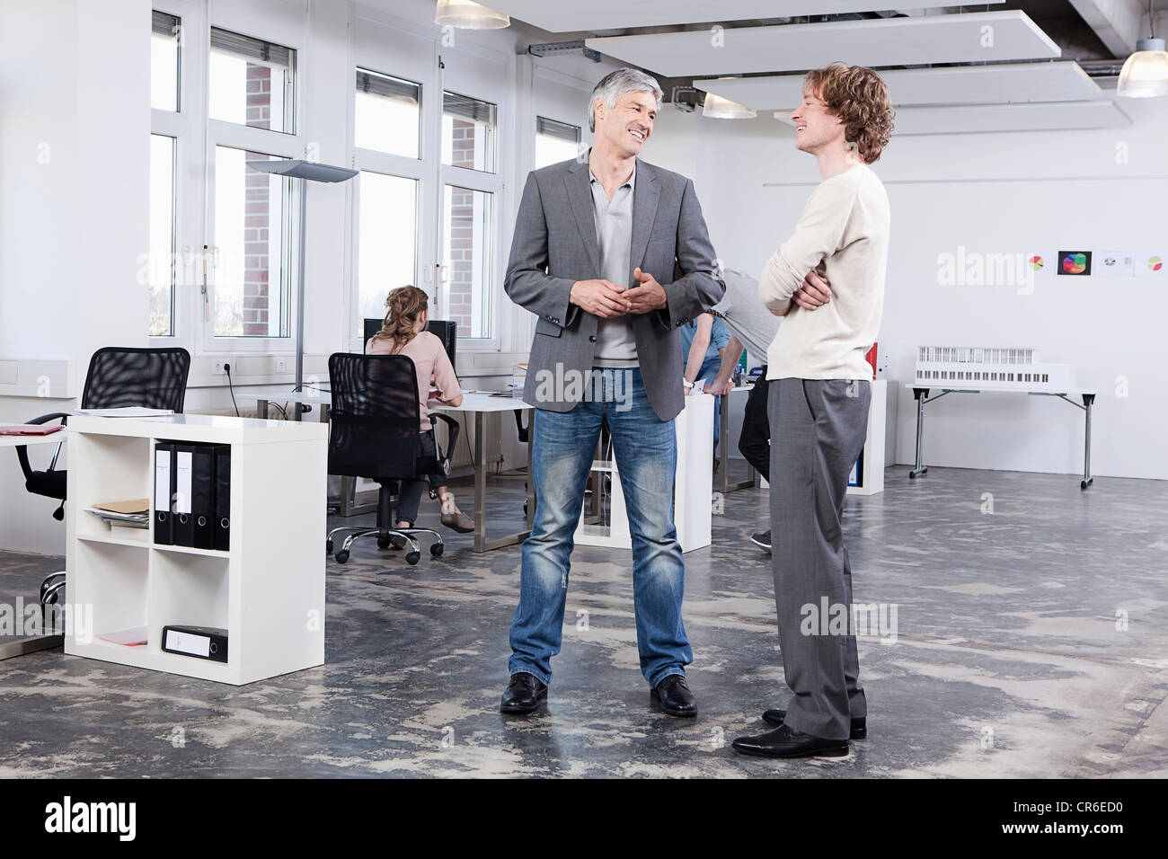 Germany, Bavaria, Munich, Men discussing, colleagues in background Stock Photo