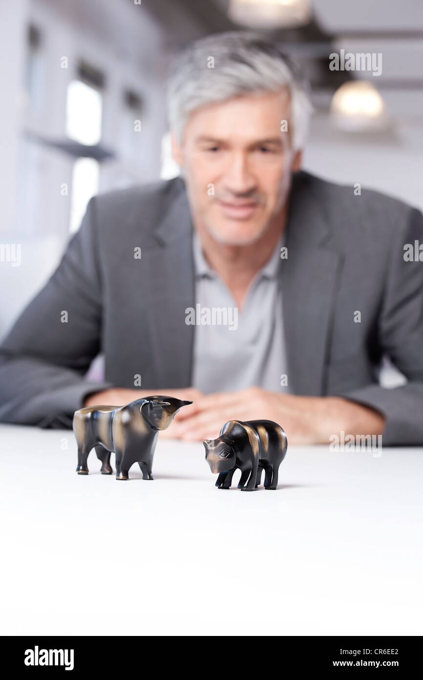 Germany, Bavaria, Munich, Mature man looking at bull and bear figurines Stock Photo