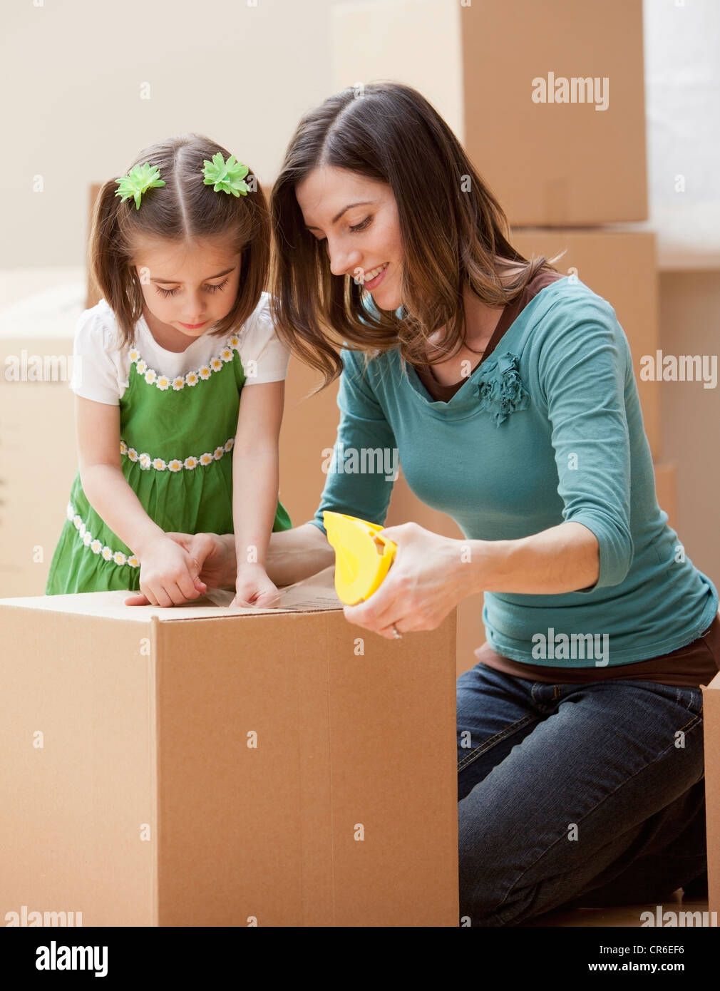 Mother with daughter (4-5) closing cardboard box Stock Photo