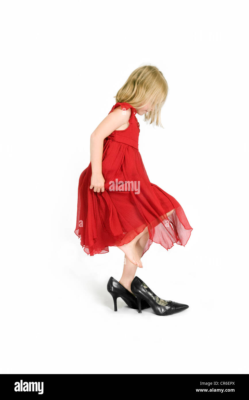Studio image of Caucasian 7 year old girl in red dress playing dress up on a white background Stock Photo
