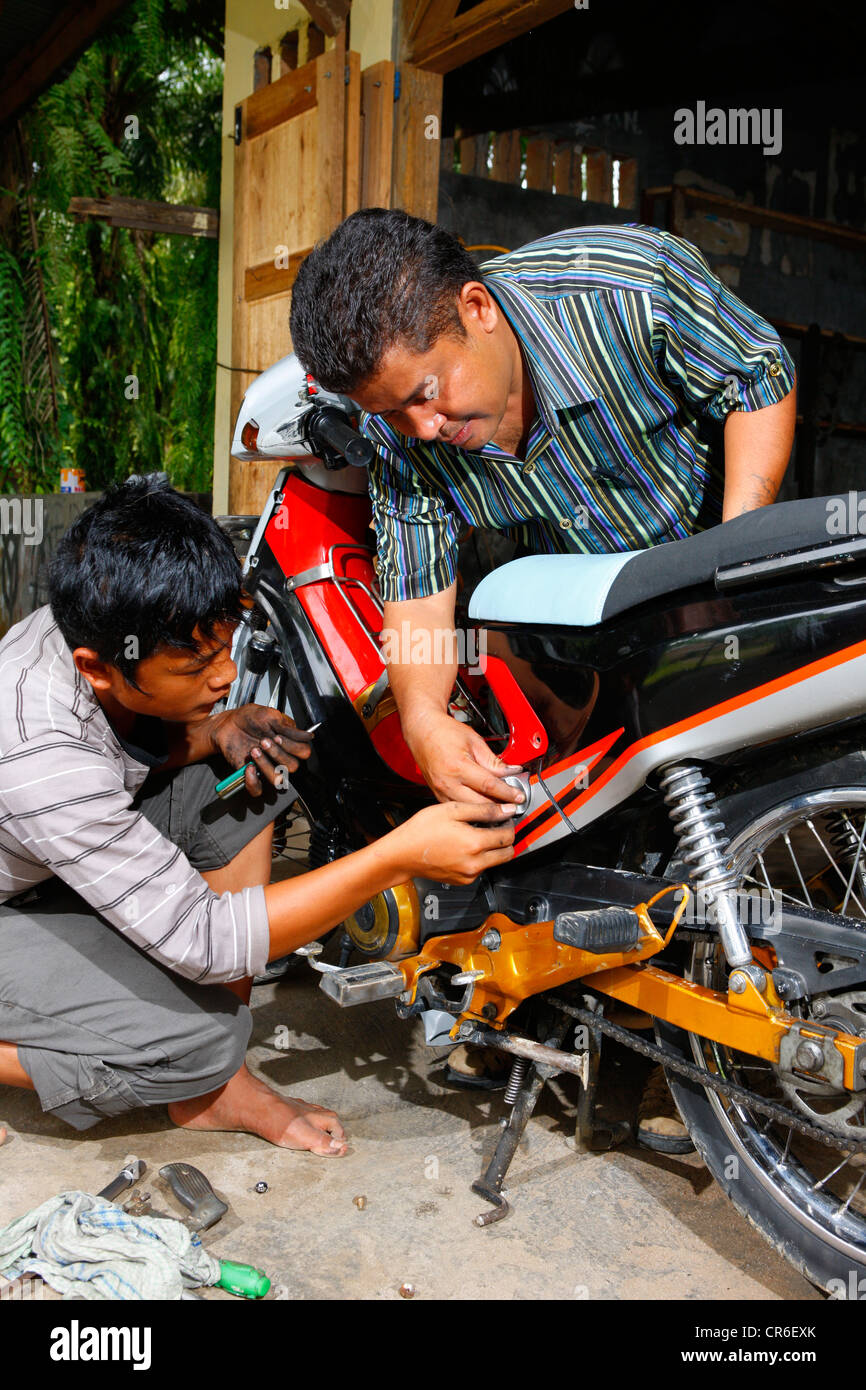 Young men repairing a motorcycle during a mechanics apprenticeship, vocational training center