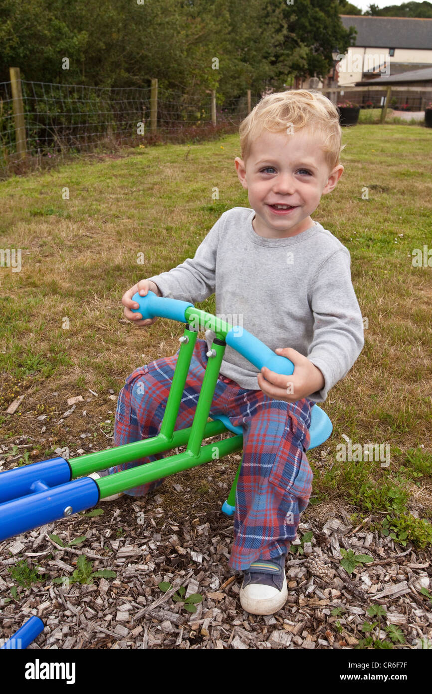 Two year old baby boy playing on a seesaw, Devon, England, United