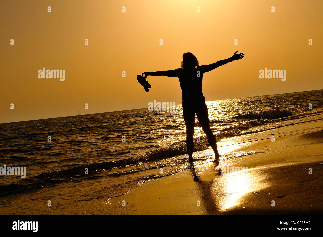 Woman standing on the beach with wide spread arms, evening mood, Lido di Ostia, Rome, Lazio region, Italy, Europe Stock Photo