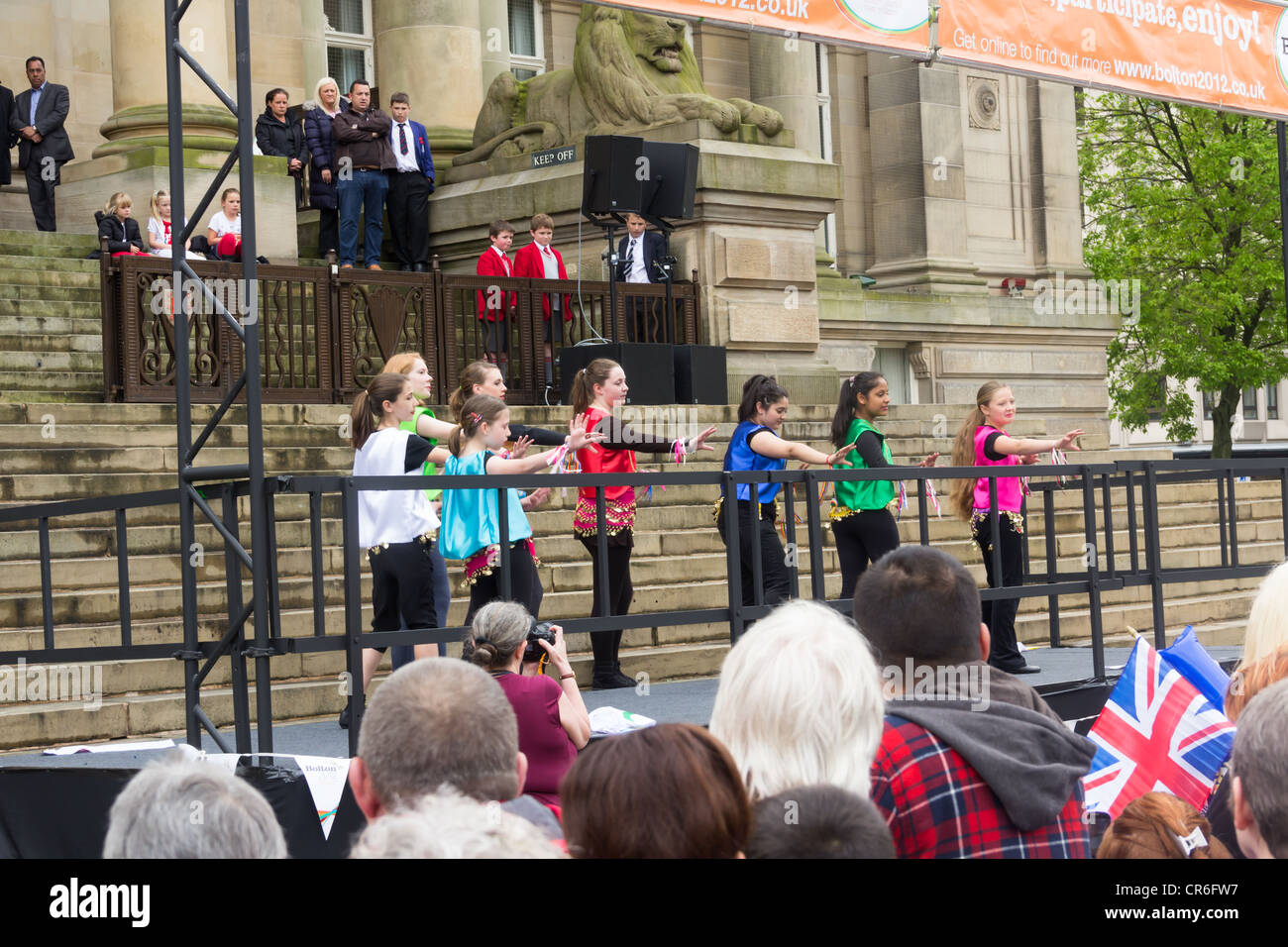 Young members of the Interfaith Ambassadors group entertain the crowd in Bolton waiting to see the arrival of the Olympic Torch. Stock Photo