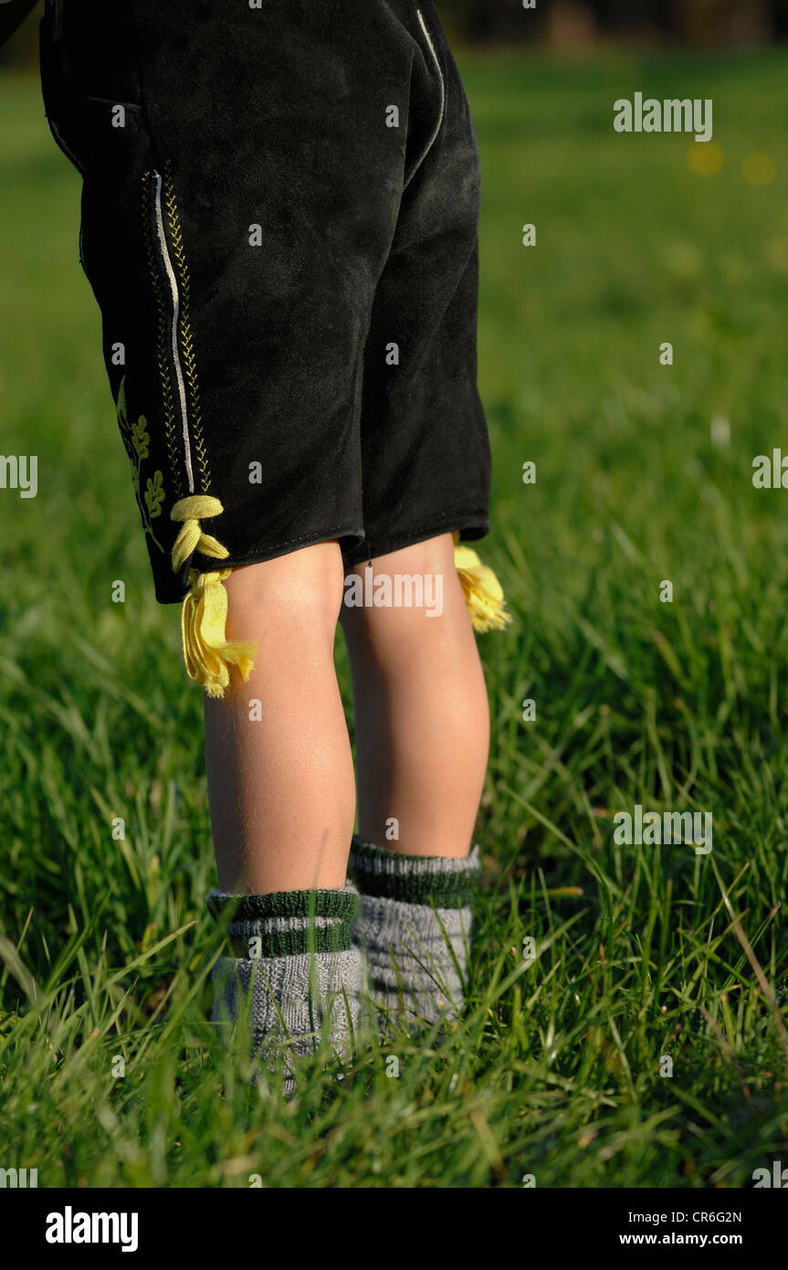 5-year old boy wearing traditional leather pants and dress socks standing in the grass Stock Photo