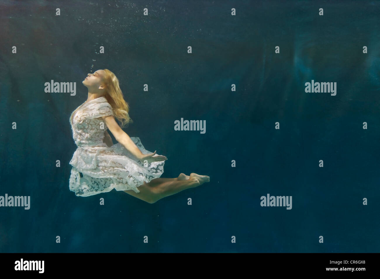 Caucasian woman in dress swimming under water Stock Photo
