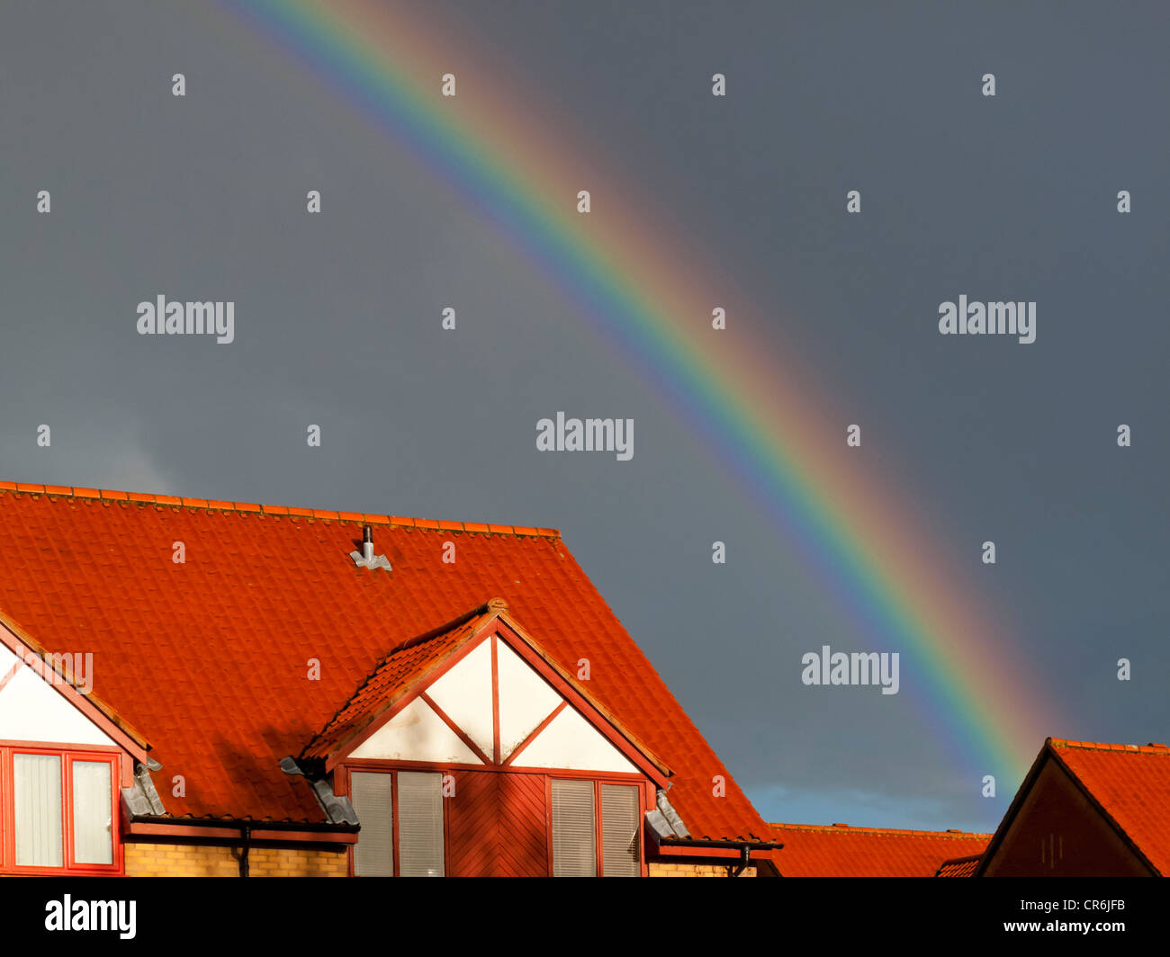 Brightly coloured rainbow with stormy sky over rooftops in Bristol ...
