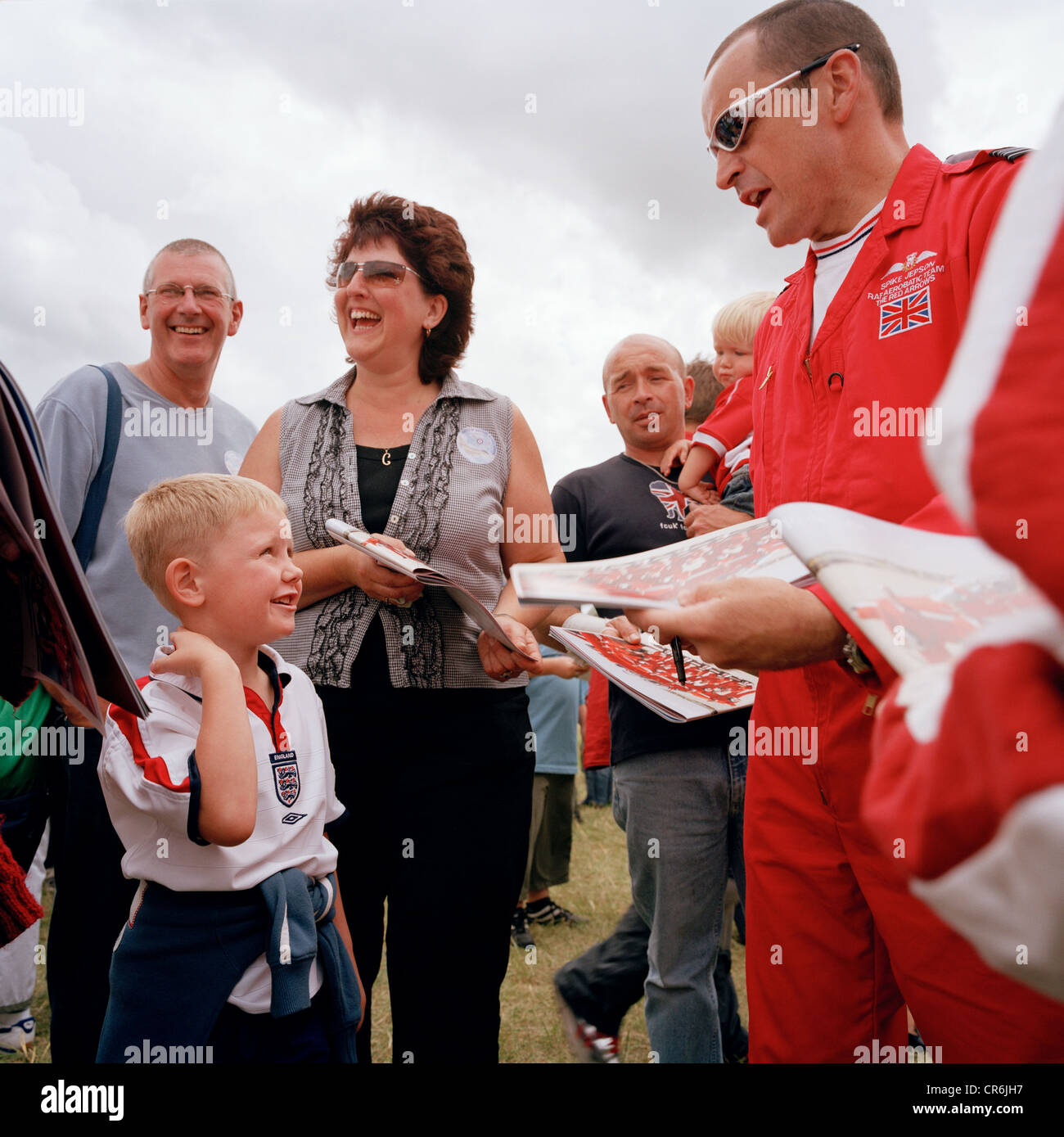 Squadron Leader Spike Jepson of the Red Arrows, Britain's RAF aerobatic team signs publicity brochures for boy during airshow. Stock Photo