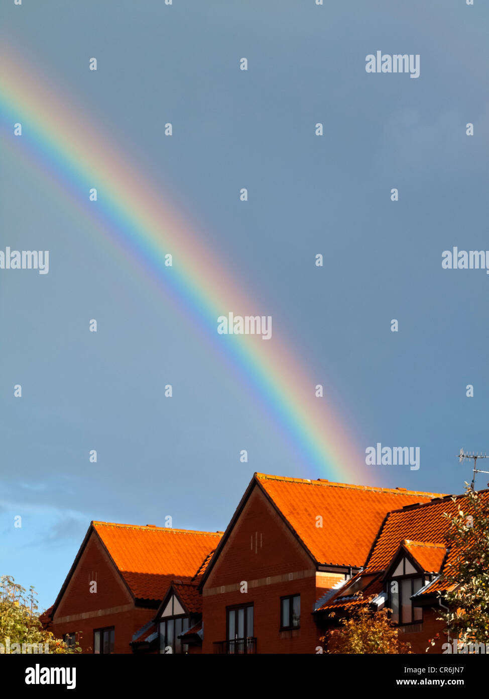 Brightly coloured rainbow with stormy sky over rooftops in Bristol ...
