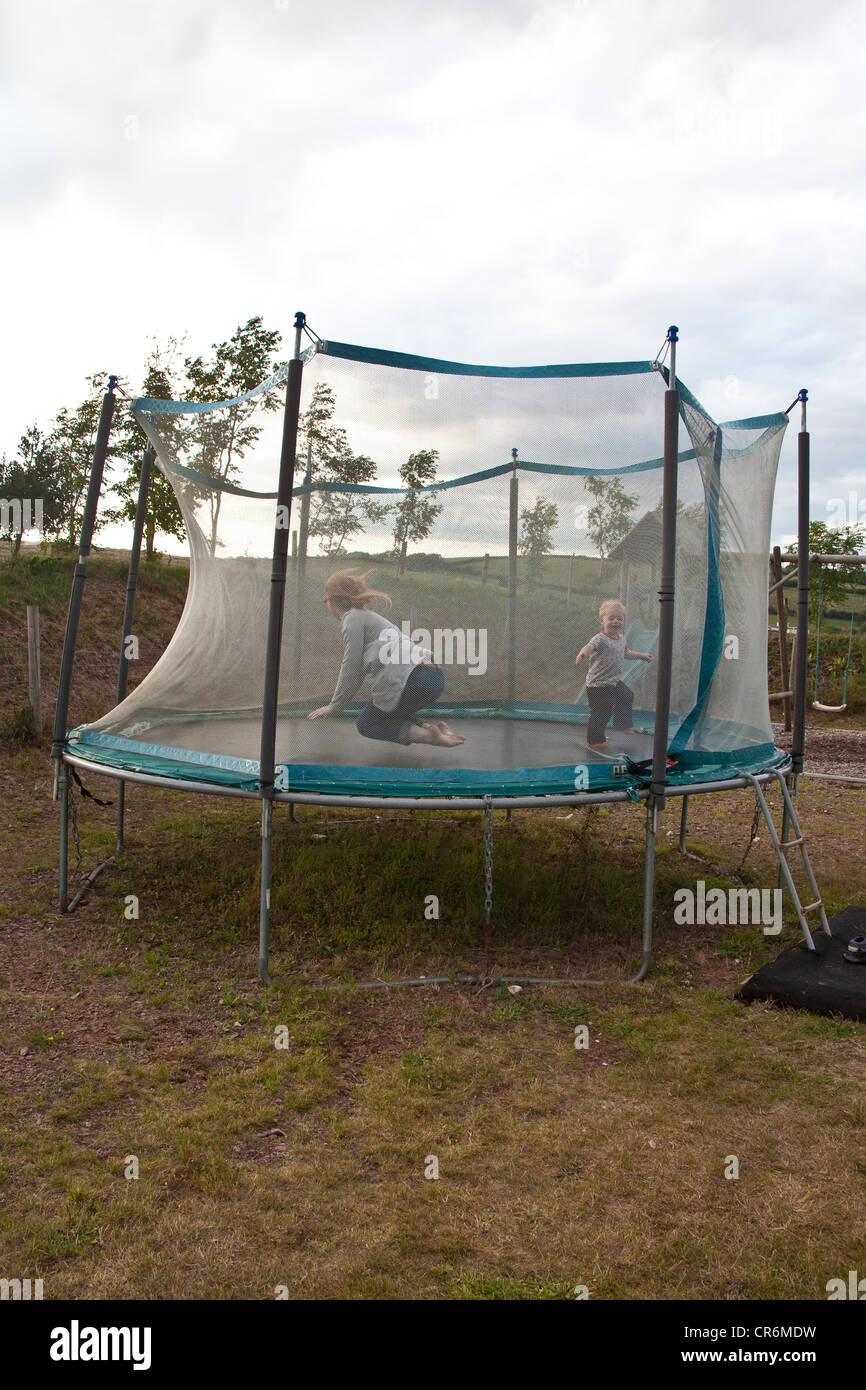 Two year old boy bouncing on a garden trampoline, Devon, england