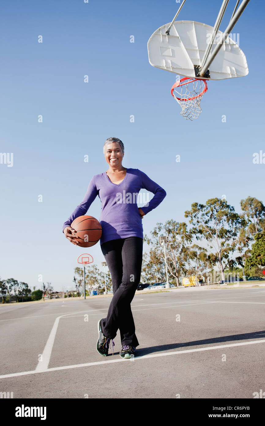 Woman holding basketball on basketball court Stock Photo - Alamy