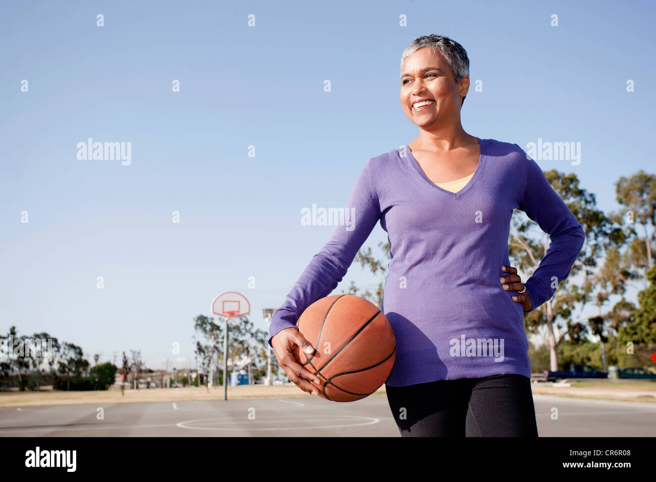Woman holding basketball on basketball court Stock Photo - Alamy