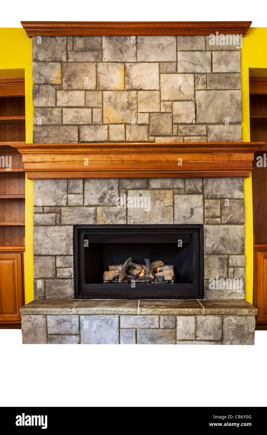 Full Vertical shot of gas insert fireplace with yellow accents walls and oak wooden shelves Stock Photo