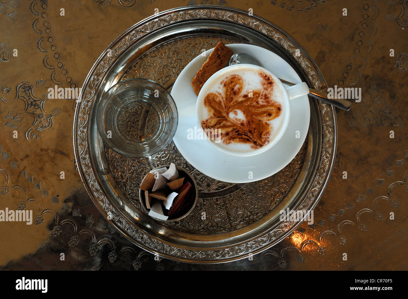 Cup of Cappuccino, glass of water and sugar sachets served on a round silver tablet with engravings, Vienna, Austria, Europe Stock Photo