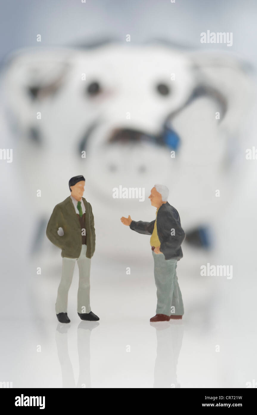 Male figurines with piggy bank on white background Stock Photo - Alamy