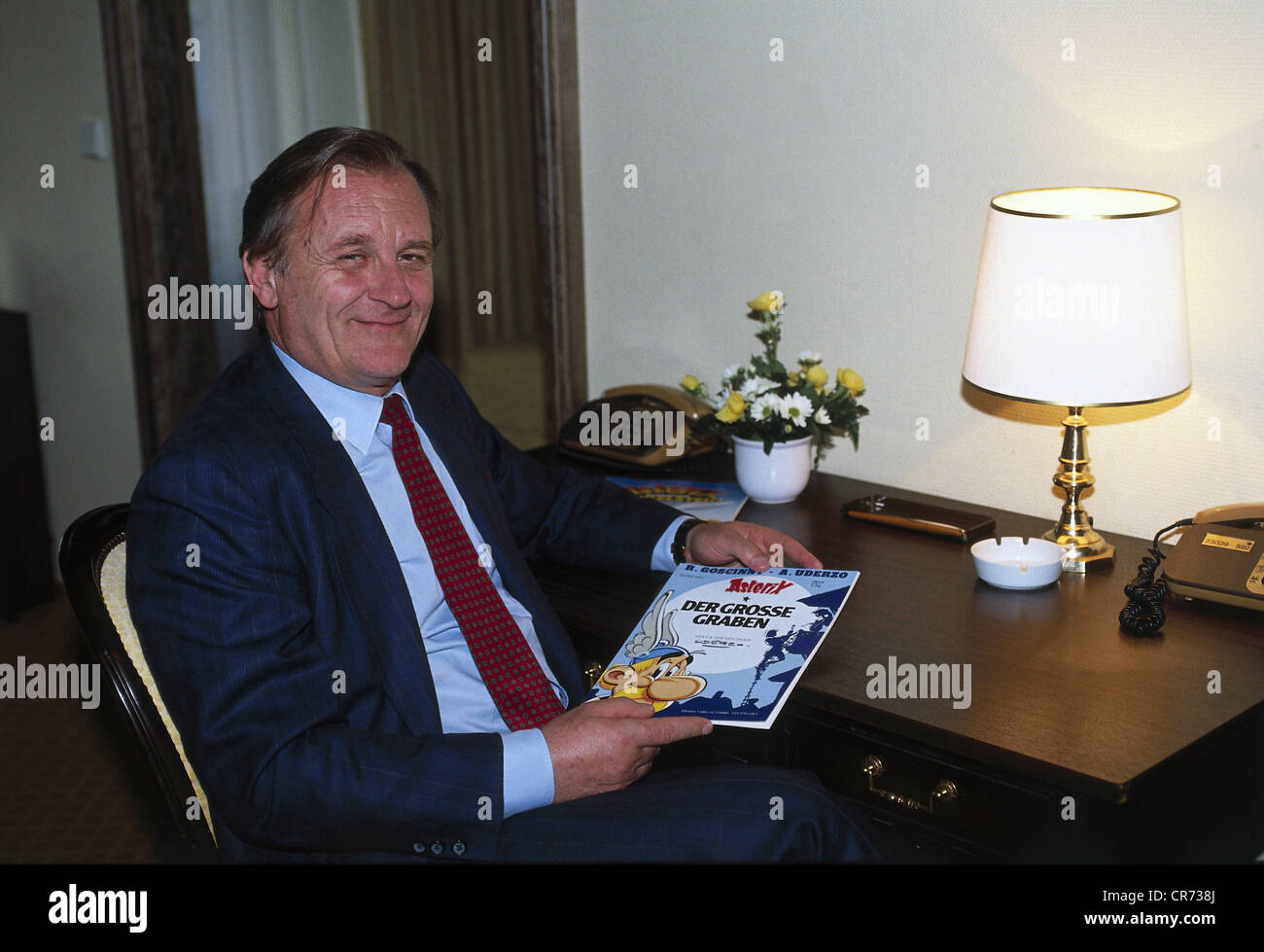 Uderzo, Albert, * 25.4.1927, French comic book artist, scriptwriter, half length, during the premiere of the movie 'Asterix - Operation Hinkelstein' in Munich, Germany, October 1989, showing his book 'Der grosse Graben' (Le Grand Fosse), Stock Photo