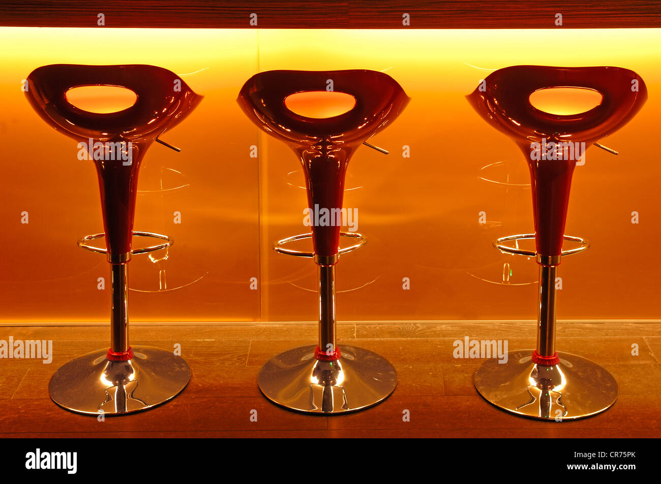 Three red plastic bar stools in front of a bar at a school of hotel