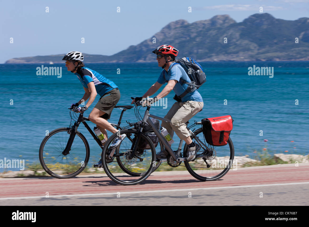 Spain, Mallorca, Man and woman cycling through road by sea Stock Photo