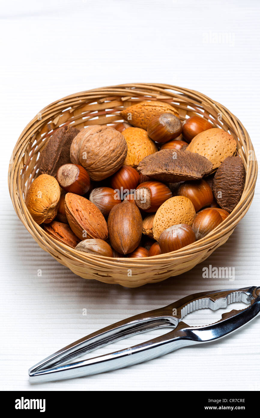 Mixed nuts in basket with nut cracker on light background Stock Photo
