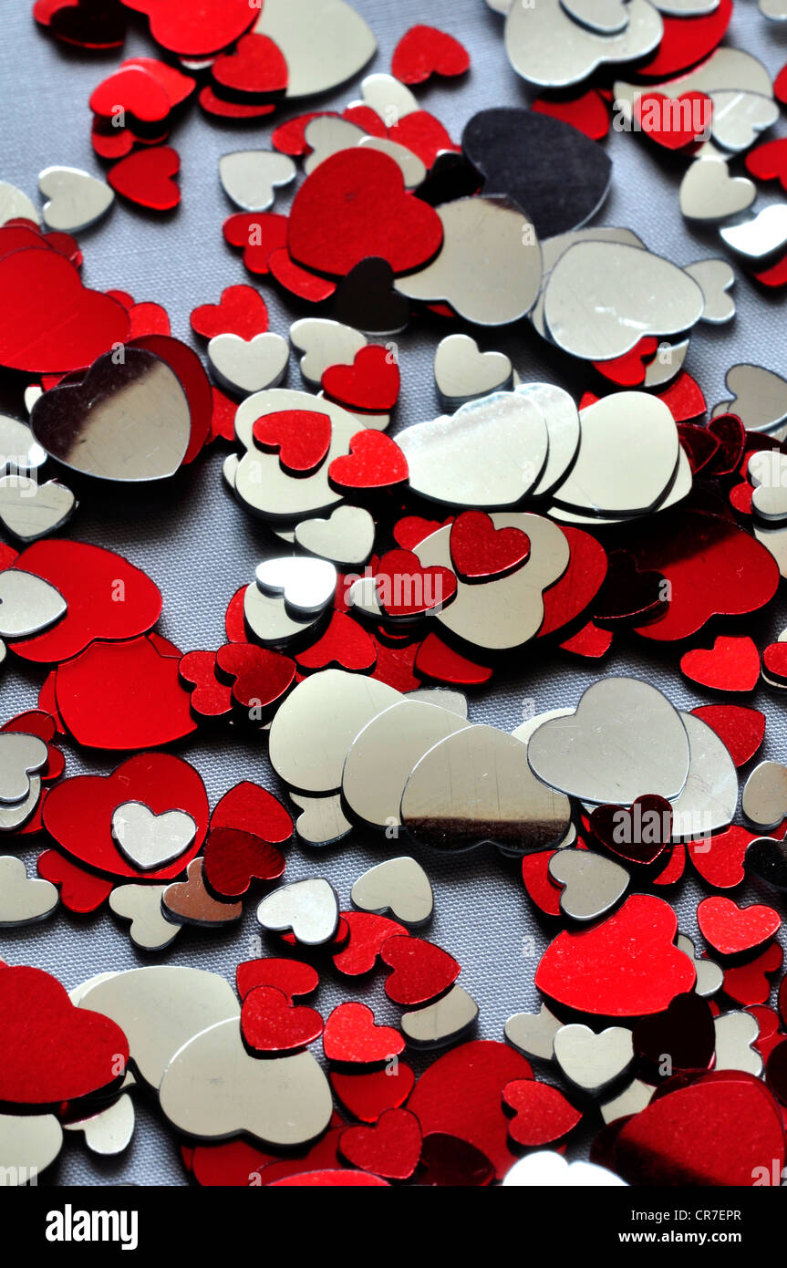 Red and silver heart confetti scattered on a cloth UK Stock Photo