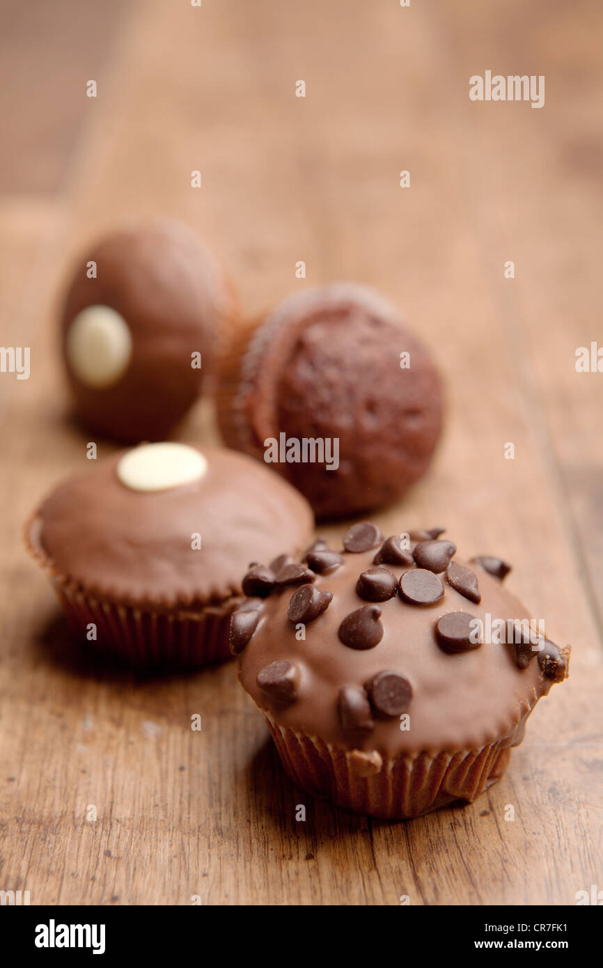 A selection of four chocolate cupcakes placed on a wooden floor background Stock Photo