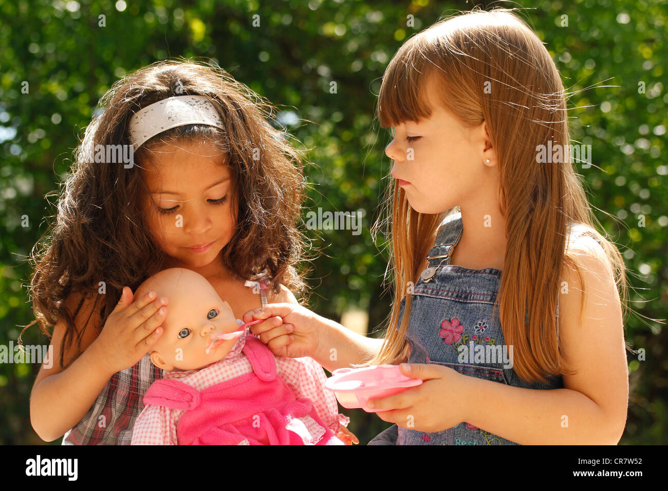 Little girls feeding a doll Stock Photo