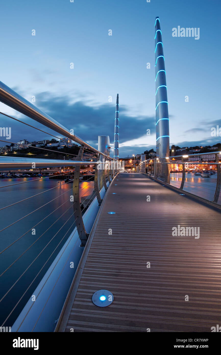 The modern footbridge spanning across the old Torquay harbour at dusk. Stock Photo