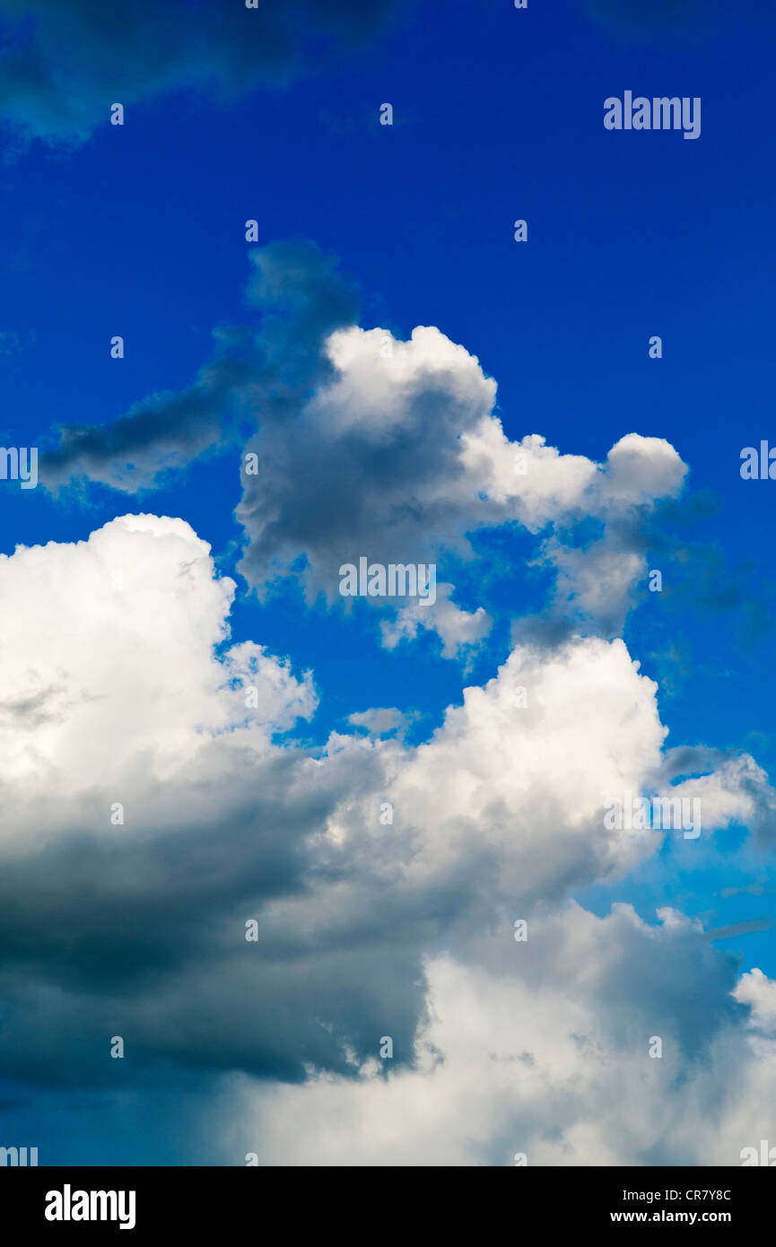 Puffy white cumulus clouds against a clear blue sky Stock Photo