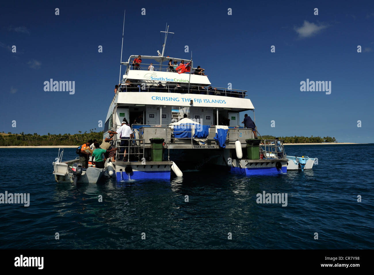 Small boats with local people and guests come alongside Yasawa Flyer which has stopped and is drifting in the Blue Lagoon. Yasawa Islands, Fiji, Stock Photo