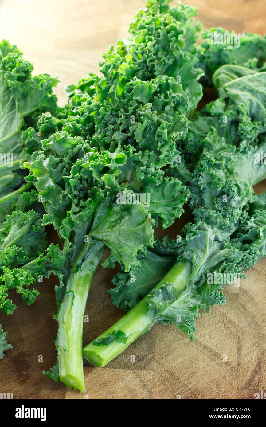 Fresh kale leaves on wooden cutting board Stock Photo