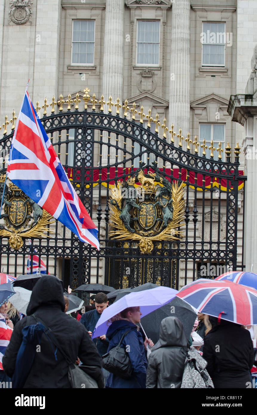 Revelers outside gates umbrellas up Queen's Diamond Jubilee celebrations Buckingham Palace Westminster London Uk 5/6/12 Stock Photo