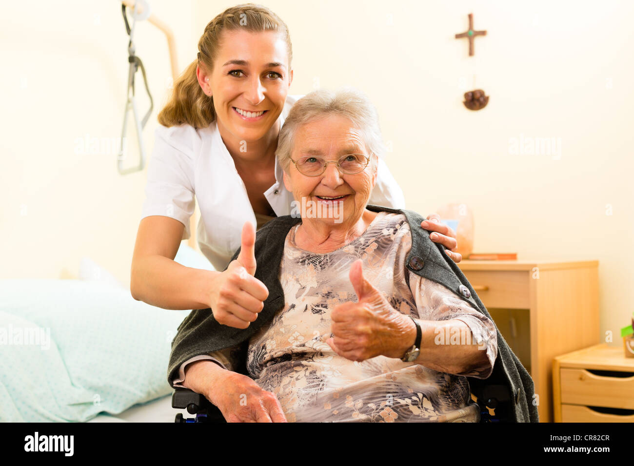Young nurse and female senior in nursing home, the old lady sitting in a wheel chair Stock Photo