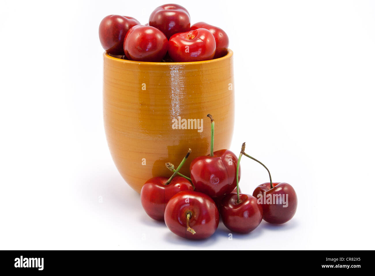 Juicy ruby red cherries in an orange cup Stock Photo