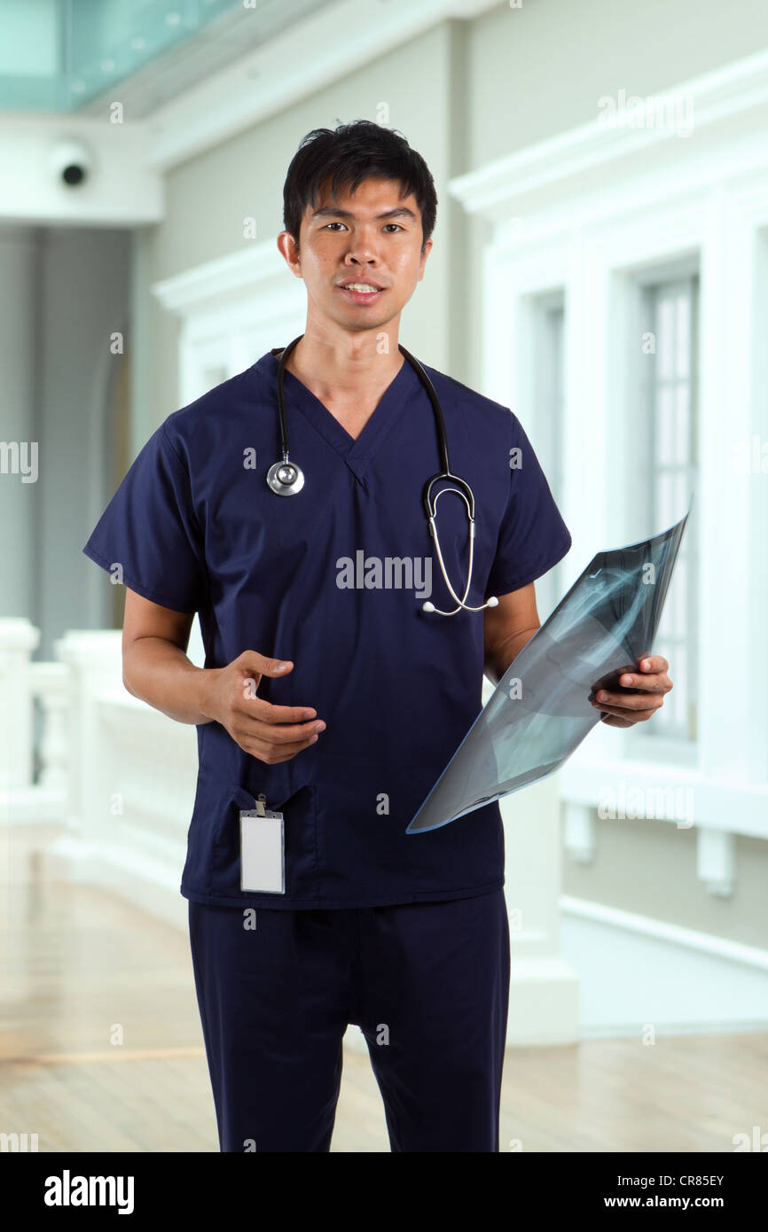 Asian doctor wearing a green scrubs, a white coat with stethoscope. Stock Photo