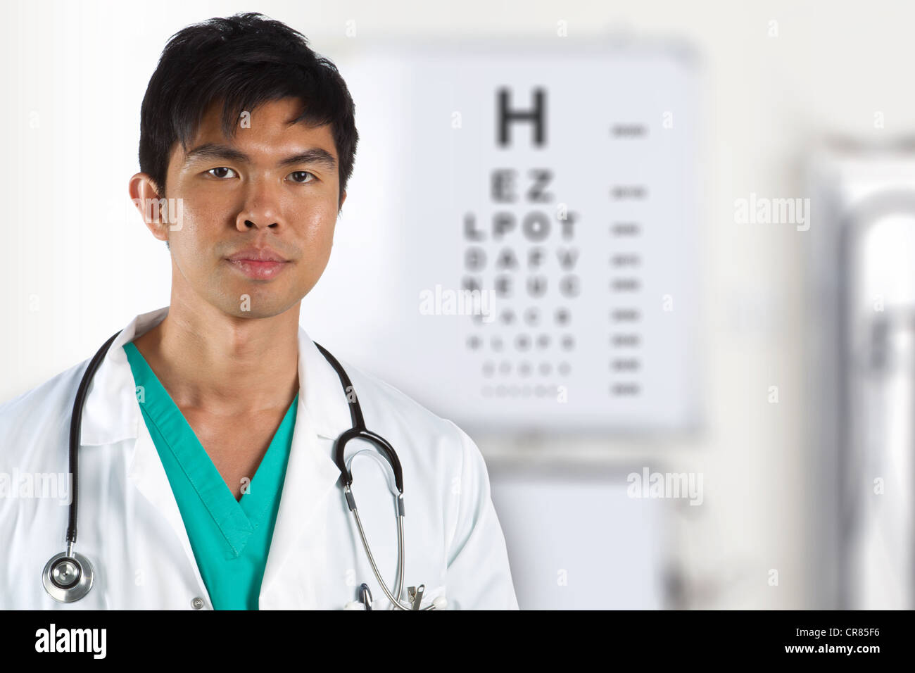 Asian doctor with an eye test chart out of focus in the background Stock Photo