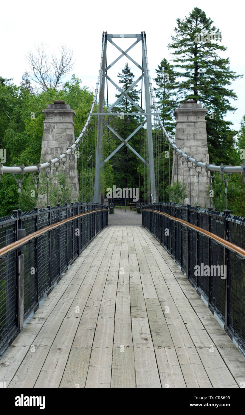 Suspension bridge with wood floor and trees in the background Stock Photo