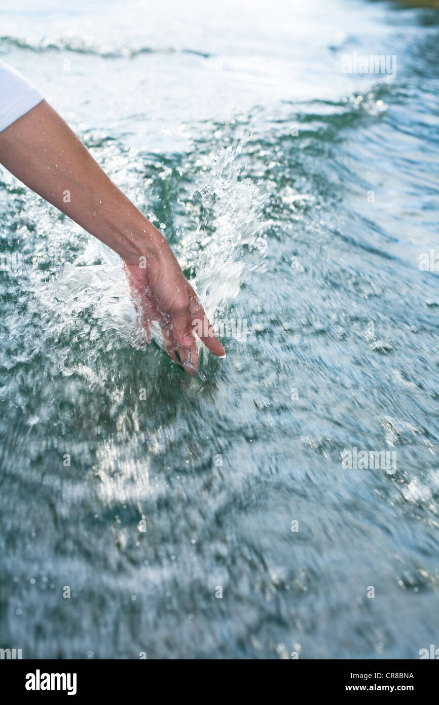Person putting hand in sea water Stock Photo