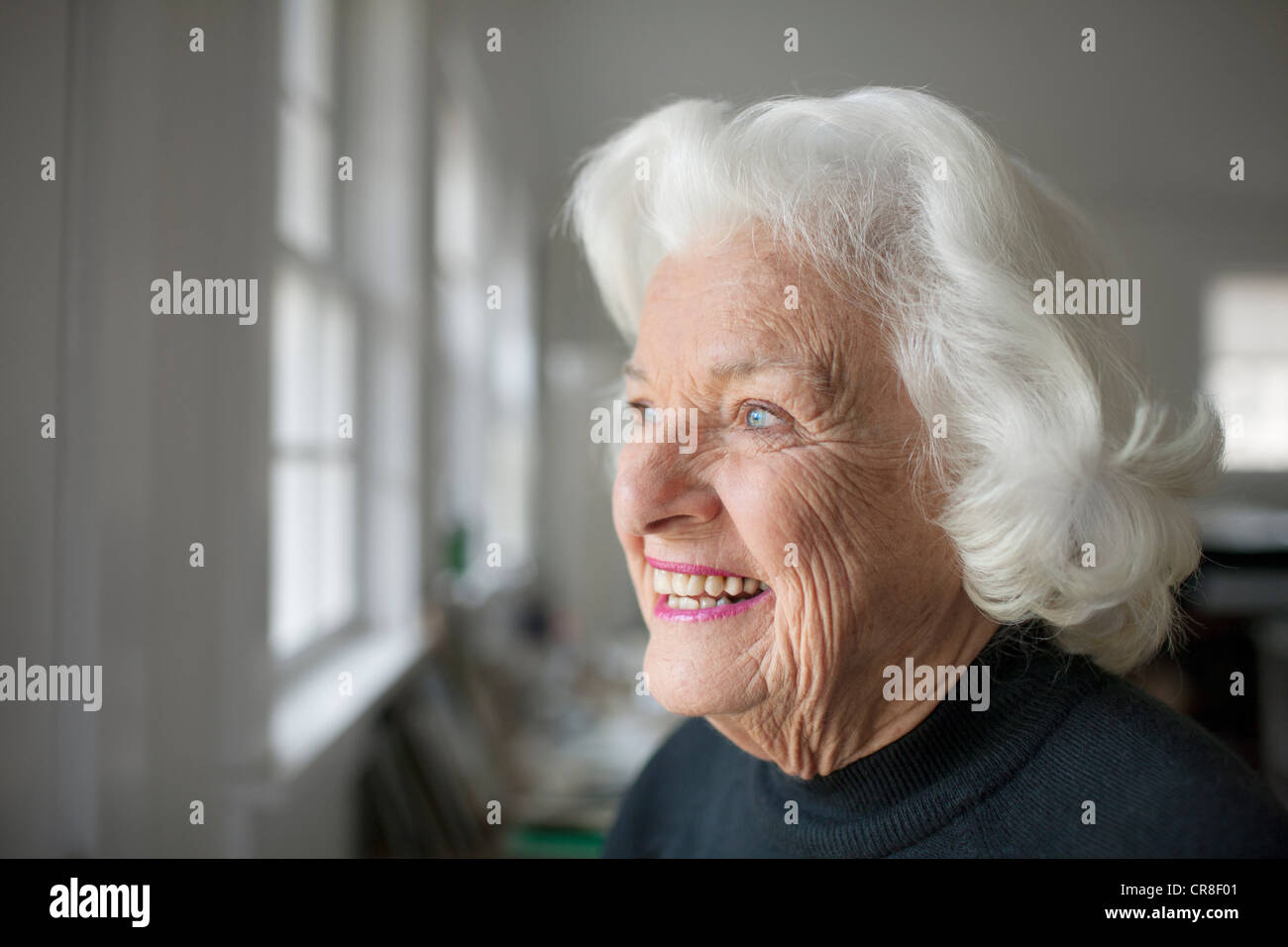 Portrait of senior woman looking out of window Stock Photo