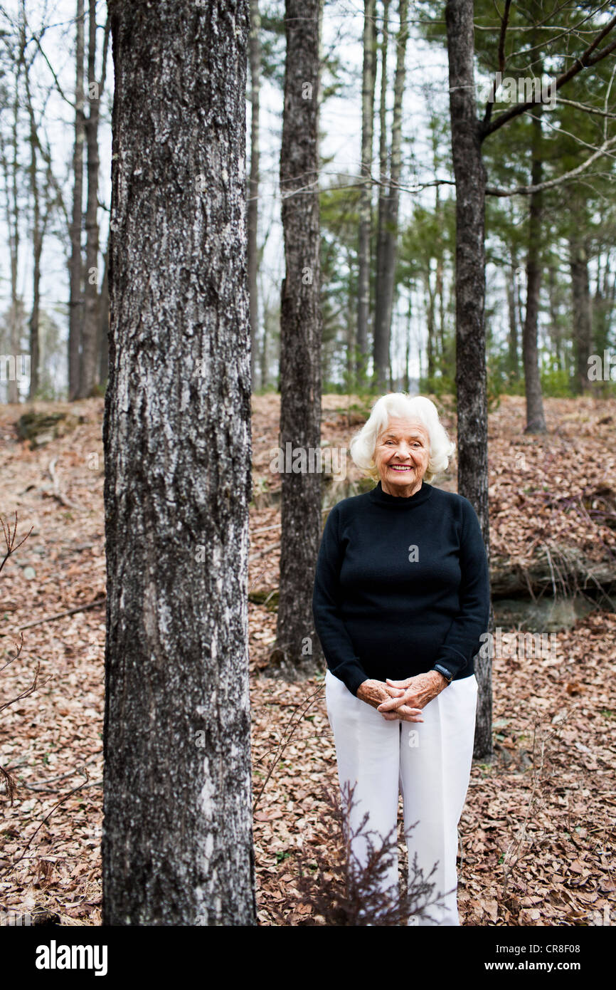 Portrait of senior woman in forest, hands clasped Stock Photo