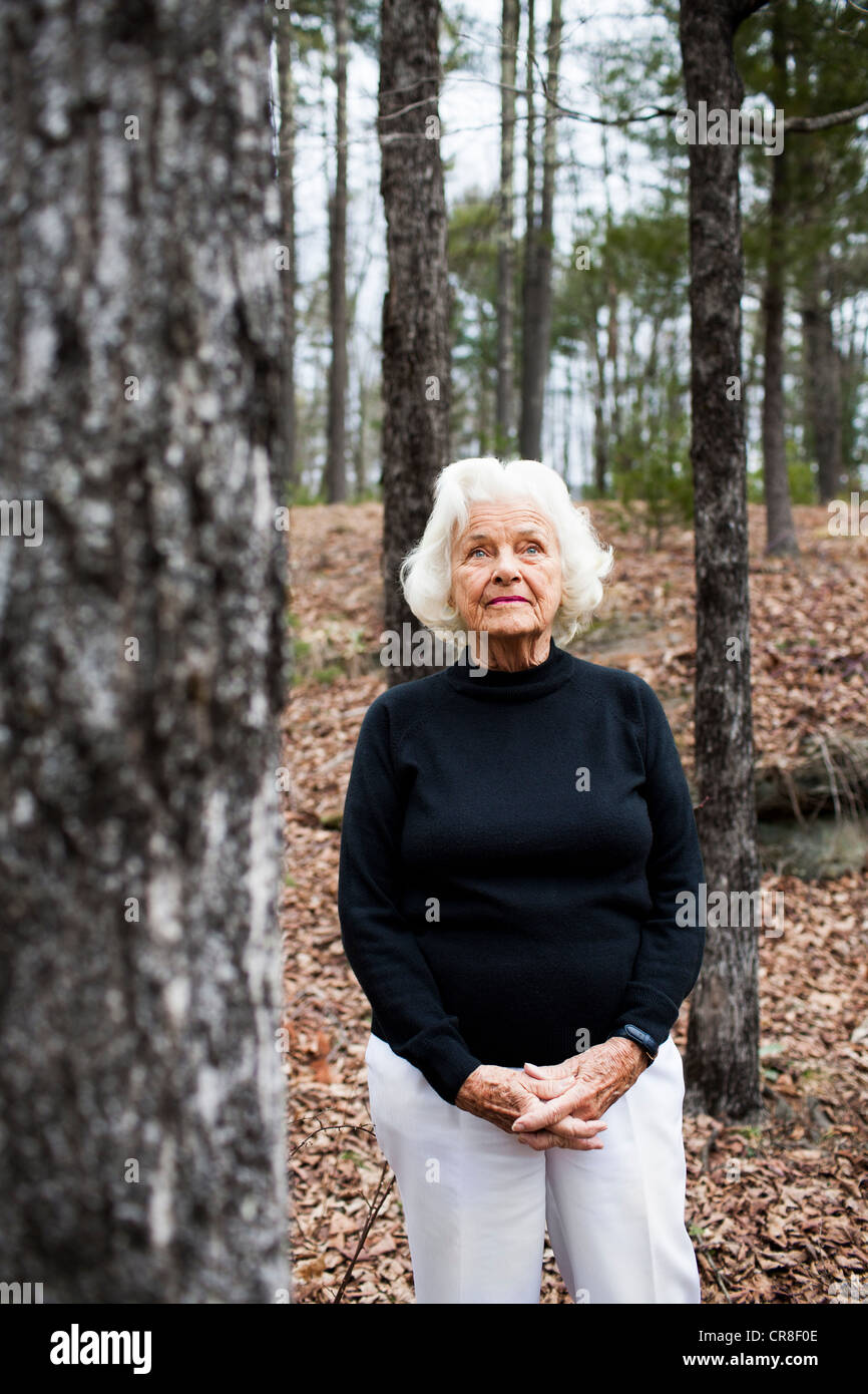 Portrait of senior woman in forest, hands clasped Stock Photo