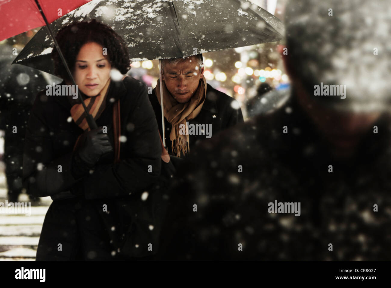 Couple walking through snow in city Stock Photo