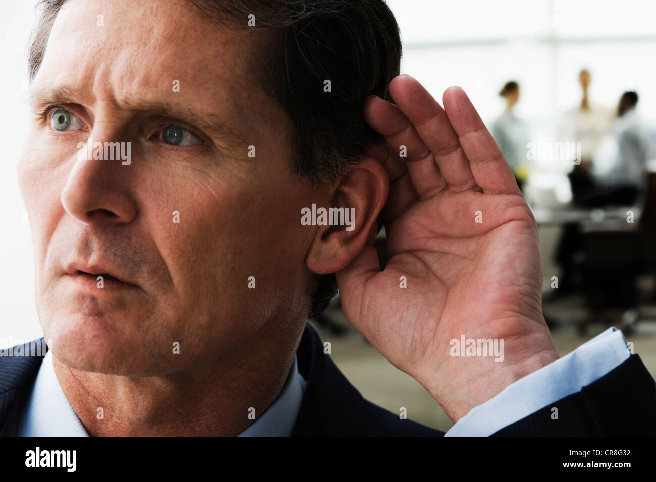 Mature businessman eavesdropping on colleagues Stock Photo