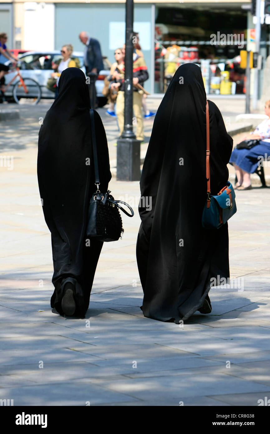 Two muslim women dressed in traditional Islamic clothing walk the