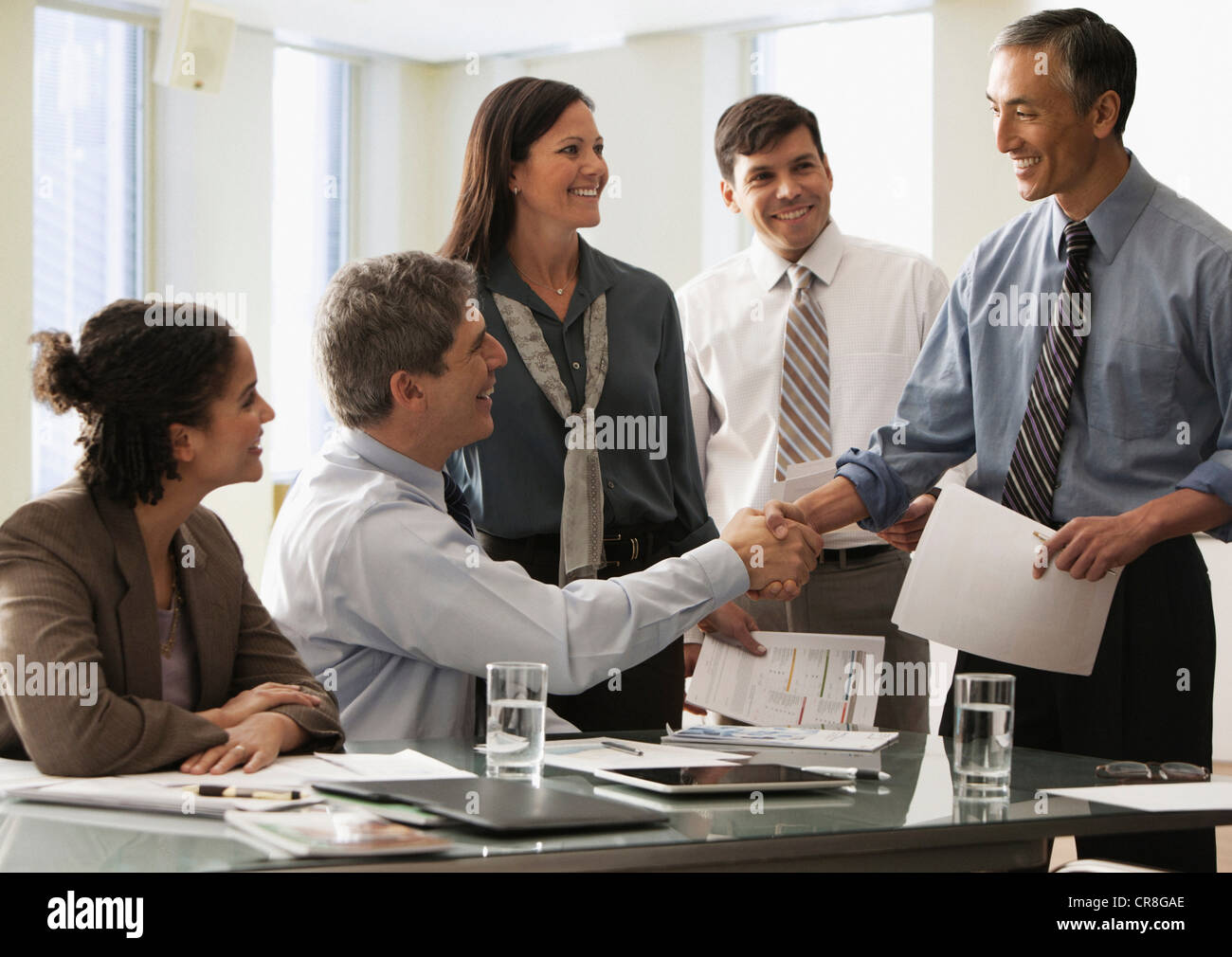 Businessman shaking hands in office with colleagues Stock Photo