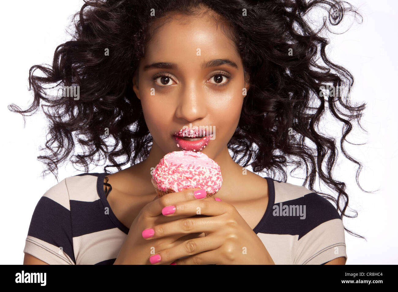 Young woman eating cupcake, studio shot Stock Photo Alamy